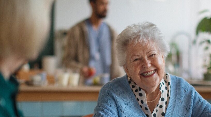Smiling elderly woman enjoying breakfast in nursing home care center.