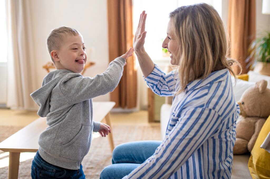 Alleinerziehende Mutter spielt mit ihrem Kind mit Down-Syndrom zu Hause.