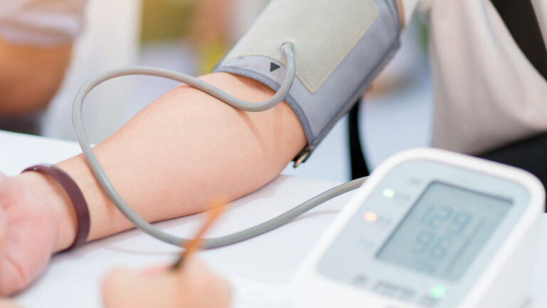 Eine Person mit hellem Hautton lässt entspannt den Blutdruck am Arm messen